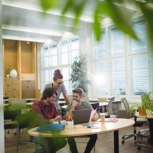 Group of business executives discussing over laptop at their desk in the office
